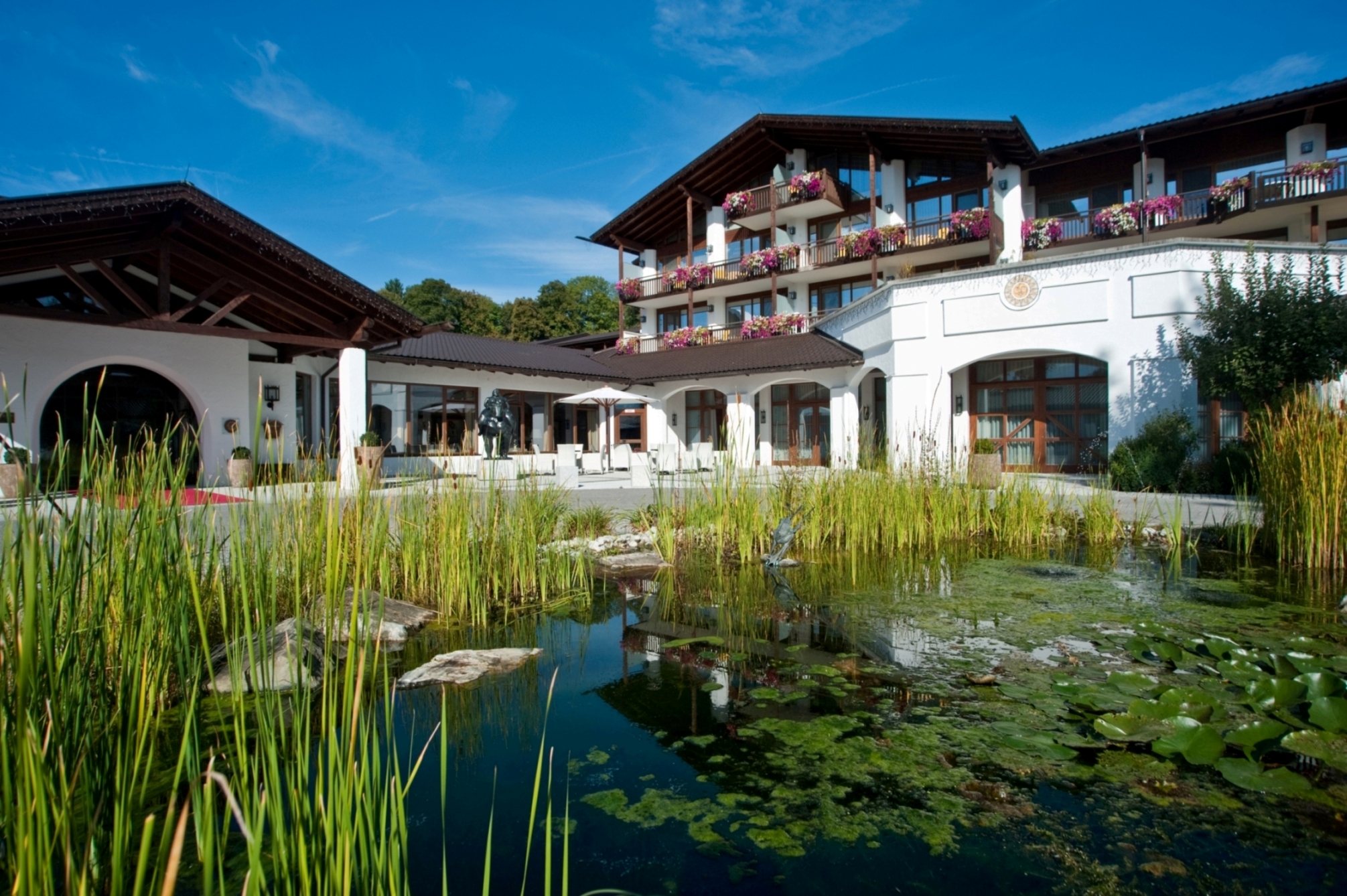 Der Alpenhof Murnau mit seiner prächtigen Außenanlage - hier mit dem großen Teich zu sehen.
