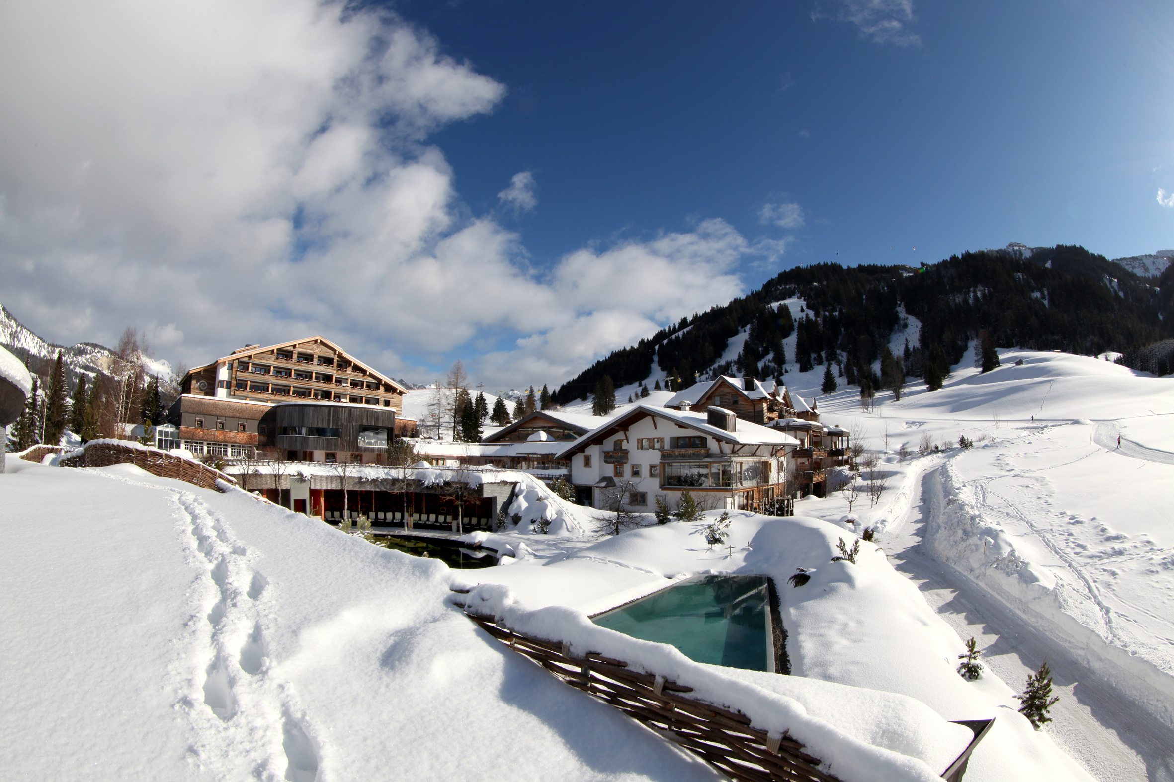 Ein stilvolles Warmbad im Winter – der Terrazzo-Außenpool im Jungbrunn Spa, des Hotel Jungbrunn Tannheim/Tirol, ist auch bei Schnee beheizt.
